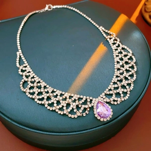 Dettaglio ravvicinato di una collana a rete d'argento con pendente viola a goccia