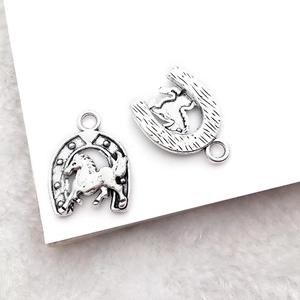 Macro detail of antique silver horseshoe and horse charms with embossed metallic textures