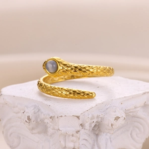 Detail of snake shaped gold ring featuring grey cat eye stone and scale texture on base