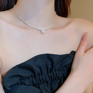 Detailed close-up of a zircon pearl pendant necklace with sparkling silver chain on neck