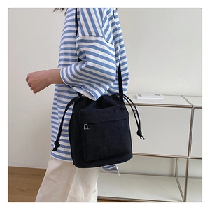 Detail of nylon drawstring shoulder bag with front zipper pocket on a model