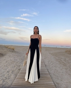 Detail of elegant black and white patchwork maxi dress flowing on a beach boardwalk