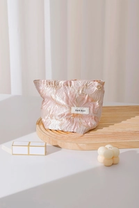 Detailed macro view of pink jacquard floral cosmetic bag with gold petal zipper pull