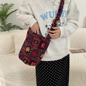 Close-up of plush crossbody bucket bag with ethnic geometric pattern on model