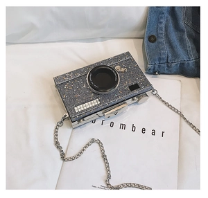 Detail of silver camera-shaped crossbody bag with star sequins and metal chain
