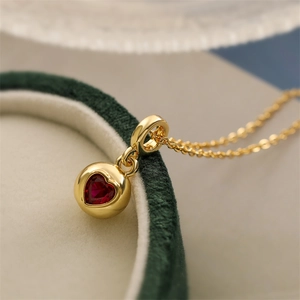 Gold plated circular pendant necklace with red heart-shaped zircon gemstone inlay