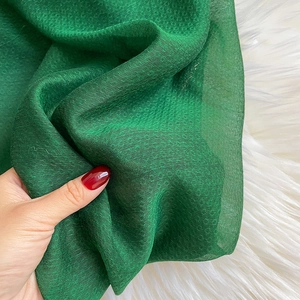 Macro shot of dark green mulberry silk fabric texture with elegant gold thread weaving
