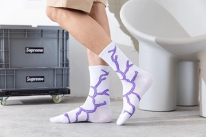 Détail de chaussettes en coton blanc avec motifs d'éclairs mauves et texture tricotée