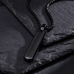 Detail of black rectangular stainless steel pendant with textured chevron pattern on stone