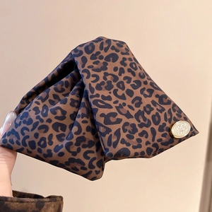 Detailed macro view of the vintage leopard print fabric texture and golden metal logo tag