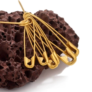 Polished gold stainless steel safety pins bundle set with volcano stone on white background