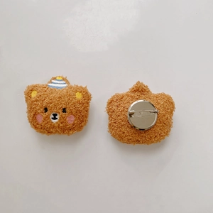 Front and back detail of plush brown bear brooch with embroidery and metal safety pin