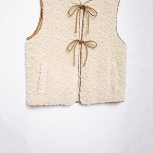 Women's cream fleece vest with tan trim and bow tie closure in a minimalist style