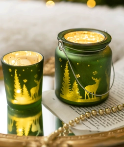 Photophore de Noël en verre dépoli vert avec silhouettes de rennes dorés et anse en métal