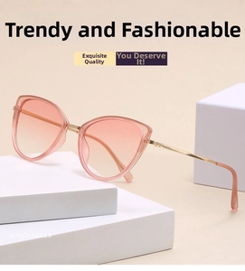 Close-up of cat-eye sunglasses with gradient pink lenses and gold metal frames on white stone