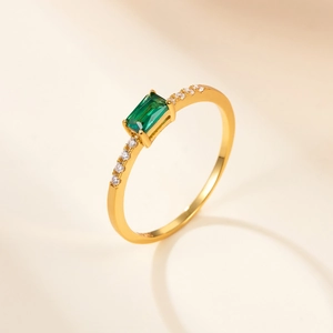 Detail view of gold ring with rectangle emerald green stone and side zircon accents