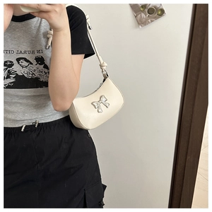 Close-up of off-white PU leather handbag featuring a silver metal bow and knotted strap
