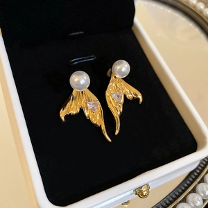 Detail of mermaid tail earrings with heart zircon and pearls on black velvet background