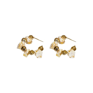 Golden C-shaped hoop earrings with textured stone-like beads on a clean white background