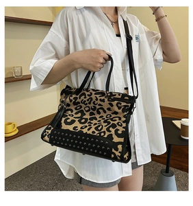 Close-up of leopard print canvas tote bag with black leather handles and tassel detail