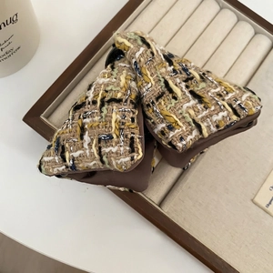 Barrette à cheveux avec nœud en tweed jaune et vert sur un plateau de bijoux
