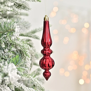 Glossy red drop-shaped Christmas ornament hanging on a snowy tree branch with warm lights
