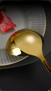 Detail of golden stainless steel spoon with high-gloss mirror polished finish