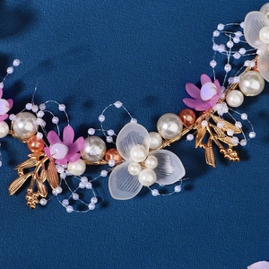 Detail of bridal headband with golden metal leaves, white pearls and purple flowers
