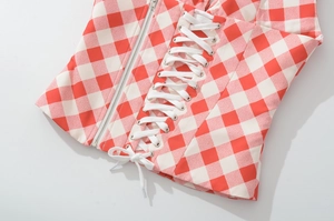 Detail of red and white plaid corset top featuring side metal zipper and front lace-up tie