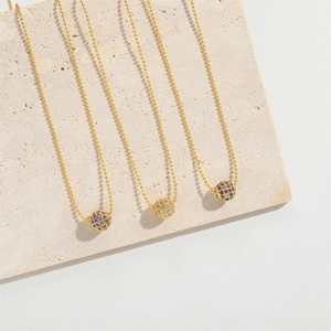 Detailed view of three gold ball chain necklaces with multi-colored cubic zirconia spheres