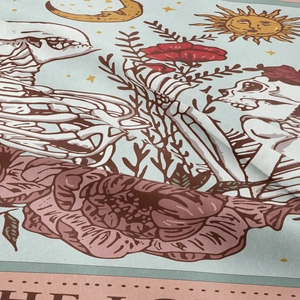 Detail of tarot tapestry fabric showing sun and moon motifs with skull art
