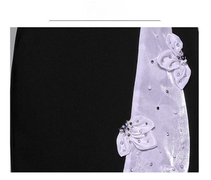 Dettaglio di abito nero con finiture in raso bianco, decori floreali e perle