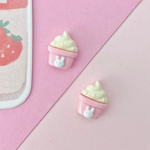 Macro detail of pink resin cupcake charms featuring cute white rabbit icons and yellow cream tops