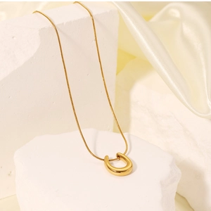 Detailed view of an 18K gold-plated U-shaped horseshoe pendant necklace on silk