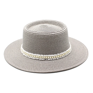 Detail of grey-brown straw sun hat featuring elegant white pearl bead trim and fine weave