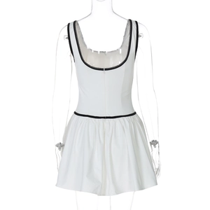 Détail d'une robe blanche sans manches avec bordures noires et une jupe courte plissée