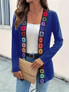 Detail of blue knit cardigan featuring colorful crochet floral embroidery on the placket