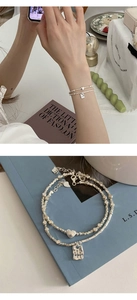 Close-up of double-layer silver bracelet with heart pendant and engraved metal square tag