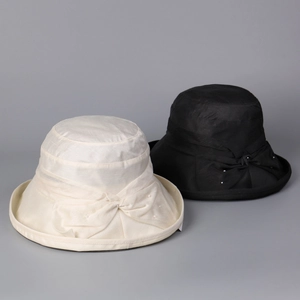 Detail of Lyocell linen blend sun hats with elegant bow and pearl accents in cream and black