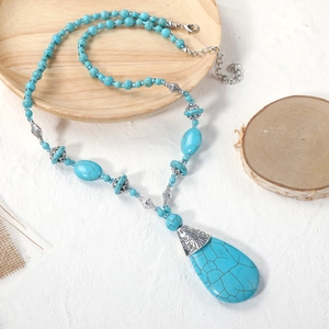 Macro detail of teardrop turquoise pendant with ornate silver filigree cap on burlap