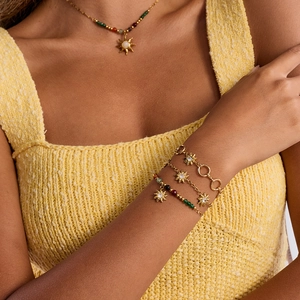 Detail of gold sun pendant necklace and layered bracelet set with colorful beads