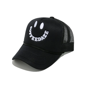 Detail of Coffee Daze smiley face embroidery on a black mesh trucker baseball hat