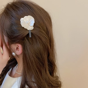Détail d'une pince à cheveux camélia avec pétales en résine crème et perle sur modèle