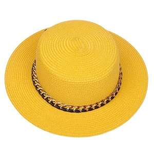 Detail shot of woven straw fedora hat texture with gold chain and black leather band