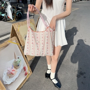 Detail of floral stripe cotton tote bag with pink checkered handles and logo patch