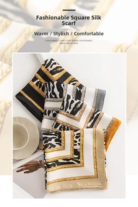Close-up of folded satin square scarves with leopard prints and gold chain patterns