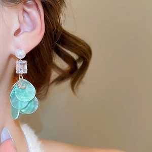 Detail view of pearl and mint green shell drop earrings with tiered zircon crystal accents