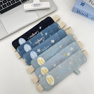Detail of denim elastic pencil cases with star embroidery and stretchable straps