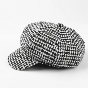 Close-up of black and white houndstooth fabric texture and button on the newsboy cap
