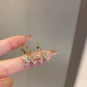 Gold plated bow knot earrings with sparkling cubic zirconia on a minimalist background